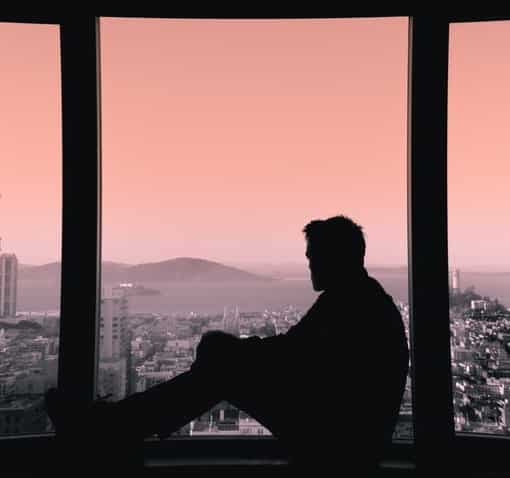 Un homme regarde l'horizon à travers une fenêtre et se soigne grâce à la Psychothérapie
